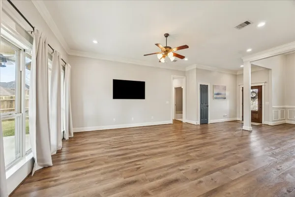 a view of an empty room with wooden floor and a window