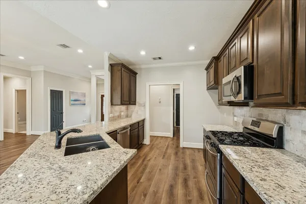 a kitchen with stainless steel appliances granite countertop a sink stove refrigerator and cabinets