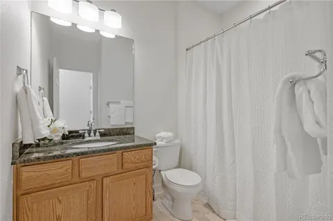 a bathroom with a granite countertop sink toilet and mirror