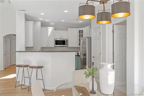 a kitchen with stainless steel appliances kitchen island granite countertop a table chairs and a refrigerator