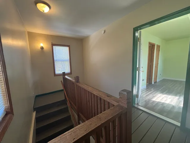 a view of a hallway with wooden floor and stairs