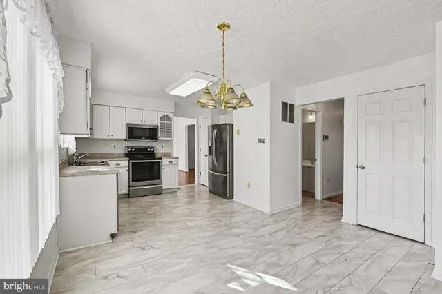 a kitchen with stainless steel appliances kitchen island granite countertop a refrigerator and a stove top oven