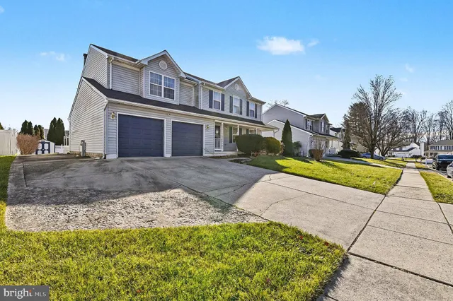 a view of a house with a small yard and large trees