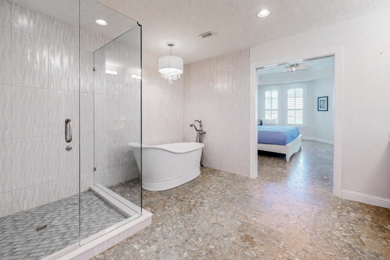 115 Sunset Harbor Way, Unit 303 St. Augustine, FL 32080 - Photo 28 of 76 Full bathroom with ensuite bath, a textured ceiling, a shower stall, tile walls, and a freestanding bath