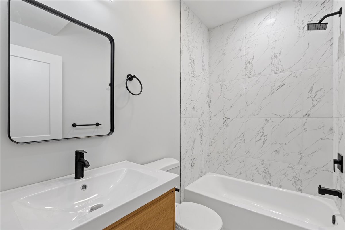 4537 South Evans Avenue, Unit 1B Chicago, IL 60653 - Photo 3 of 7 a bathroom with a tub sink toilet and mirror