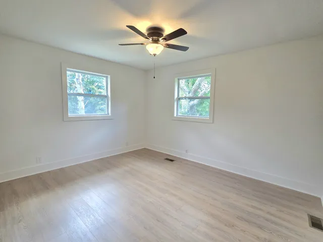 an empty room with wooden floor and windows