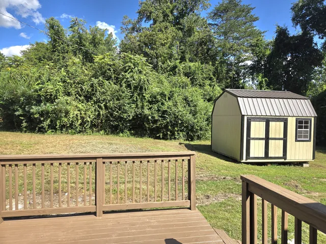 a white house that has a small yard and large trees