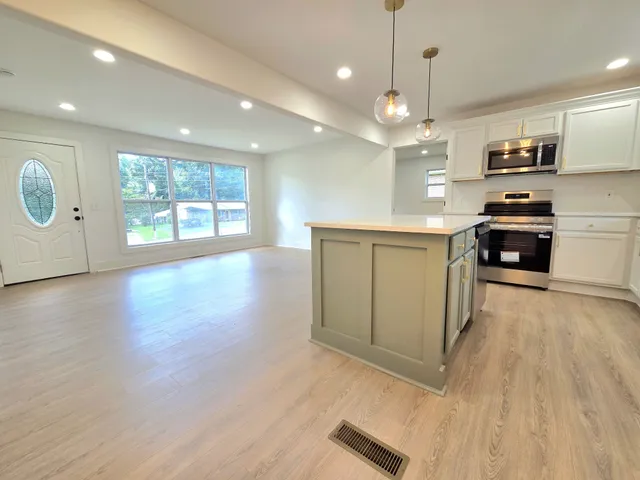 a kitchen with stainless steel appliances granite countertop a stove top oven a sink with wooden floors