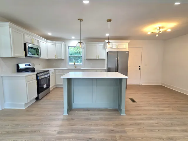 a kitchen with kitchen island a sink stainless steel appliances and cabinets