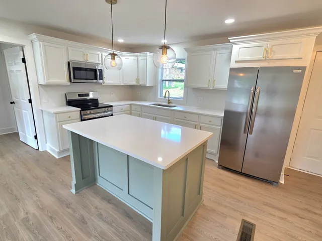 a kitchen with granite countertop a refrigerator a sink a stove a microwave and wooden floor