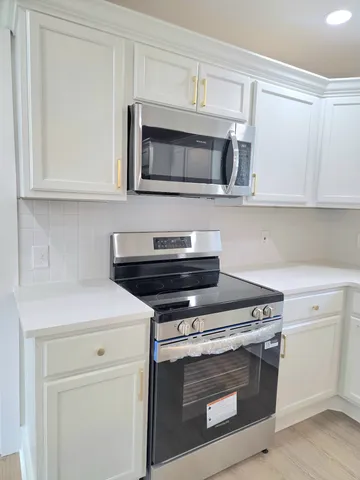 a kitchen with white cabinets and stainless steel appliances
