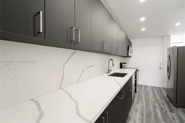 a kitchen with stainless steel appliances a sink a stove a refrigerator cabinets and a counter top space