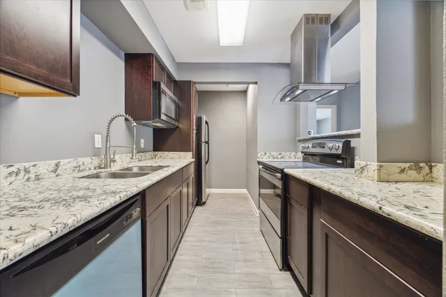a kitchen with granite countertop kitchen island stainless steel appliances a sink stove and cabinets