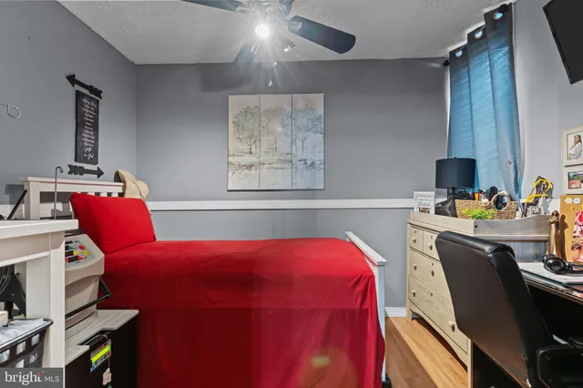 a bedroom with a bed and a computer on a desk next to a window