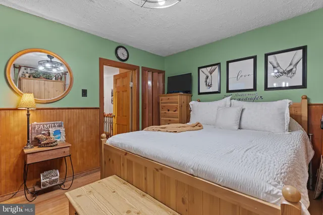 a spacious bedroom with a bed and a mirror on the dresser