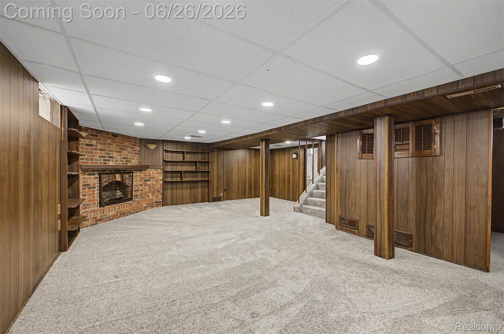 2216 Banner Street Dearborn, MI 48124 - Photo 23 of 34 Spacious finished lower level featuring wood-finish paneling, an exposed brick fireplace with a mantel, built-in shelving, recessed lighting, and light gray carpeting