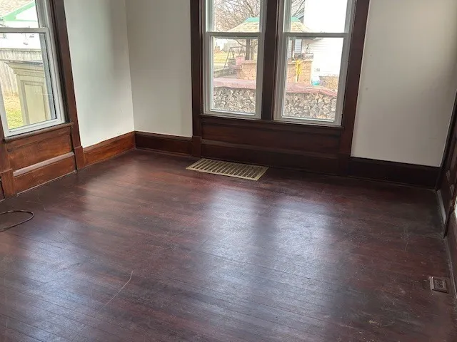 an empty room with wooden floor and windows