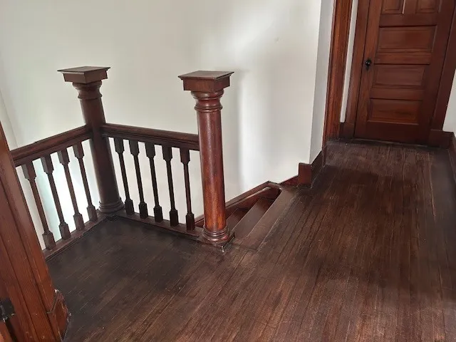 a view of a hallway with wooden floor and stairs