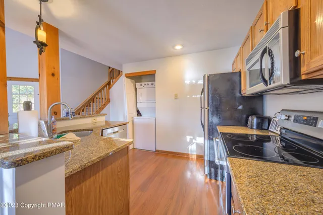 a kitchen with stainless steel appliances granite countertop a refrigerator a stove and a sink with wooden floor