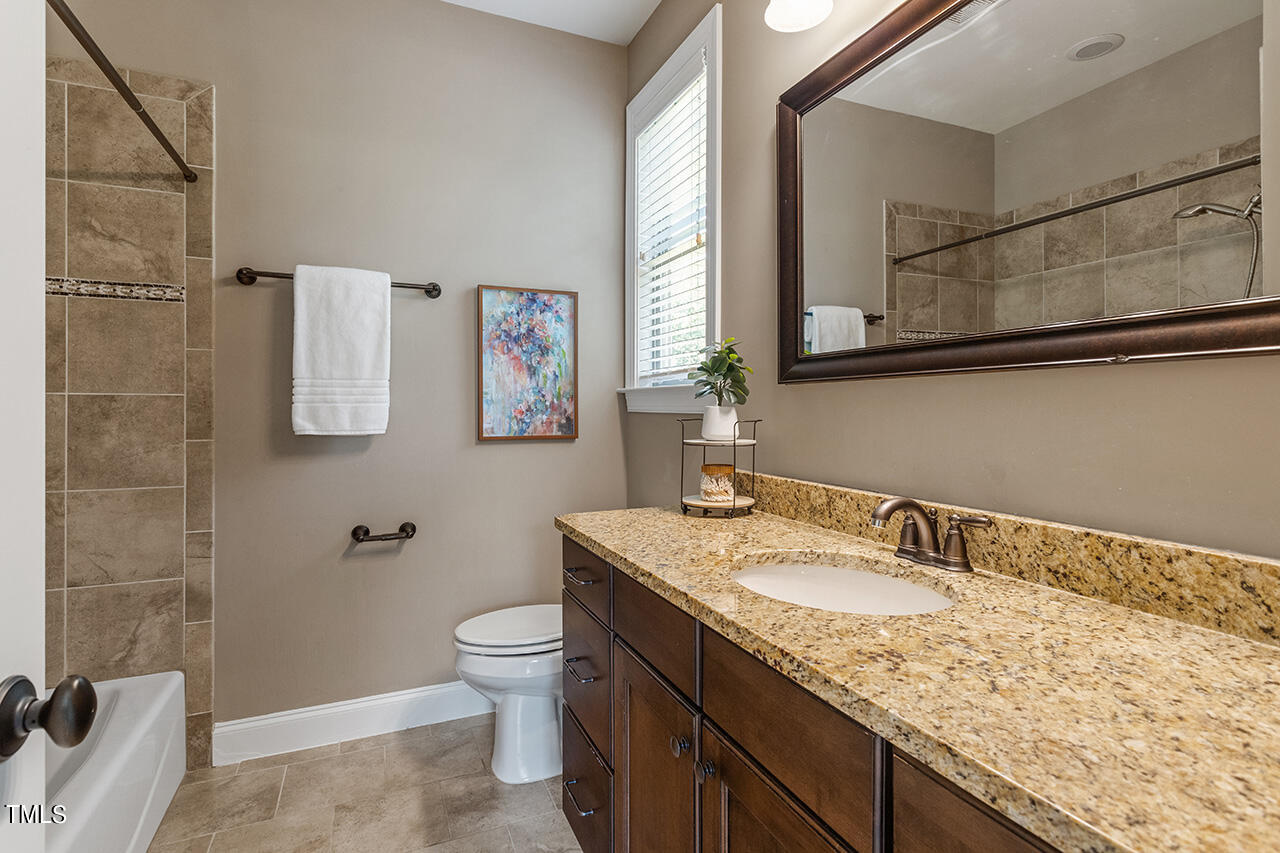 1036 Quiet Ridge Circle Raleigh, NC 27614 - Photo 49 of 60 a bathroom with a granite countertop sink a toilet a mirror and shower