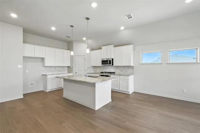 a kitchen with stainless steel appliances white cabinets a sink a stove a refrigerator and a oven