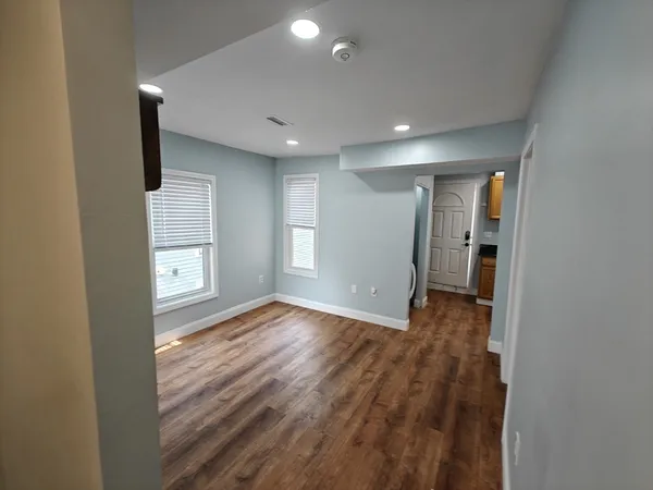 a view of empty room with wooden floor and fan
