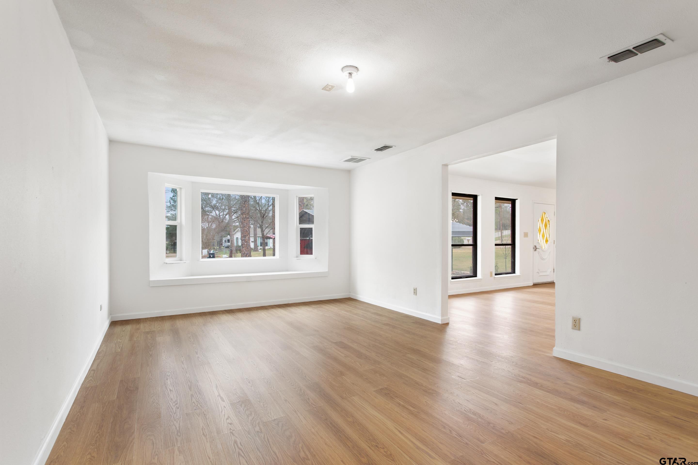 208 Treetop Lane Hideaway, TX 75771 - Photo 8 of 32 a view of an empty room with wooden floor and a window