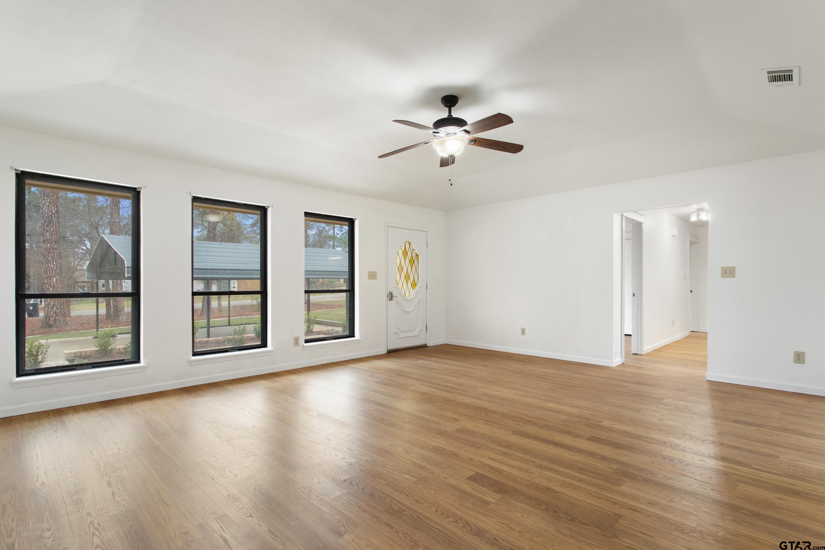 208 Treetop Lane Hideaway, TX 75771 - Photo 9 of 32 a view of an empty room with a window and wooden floor