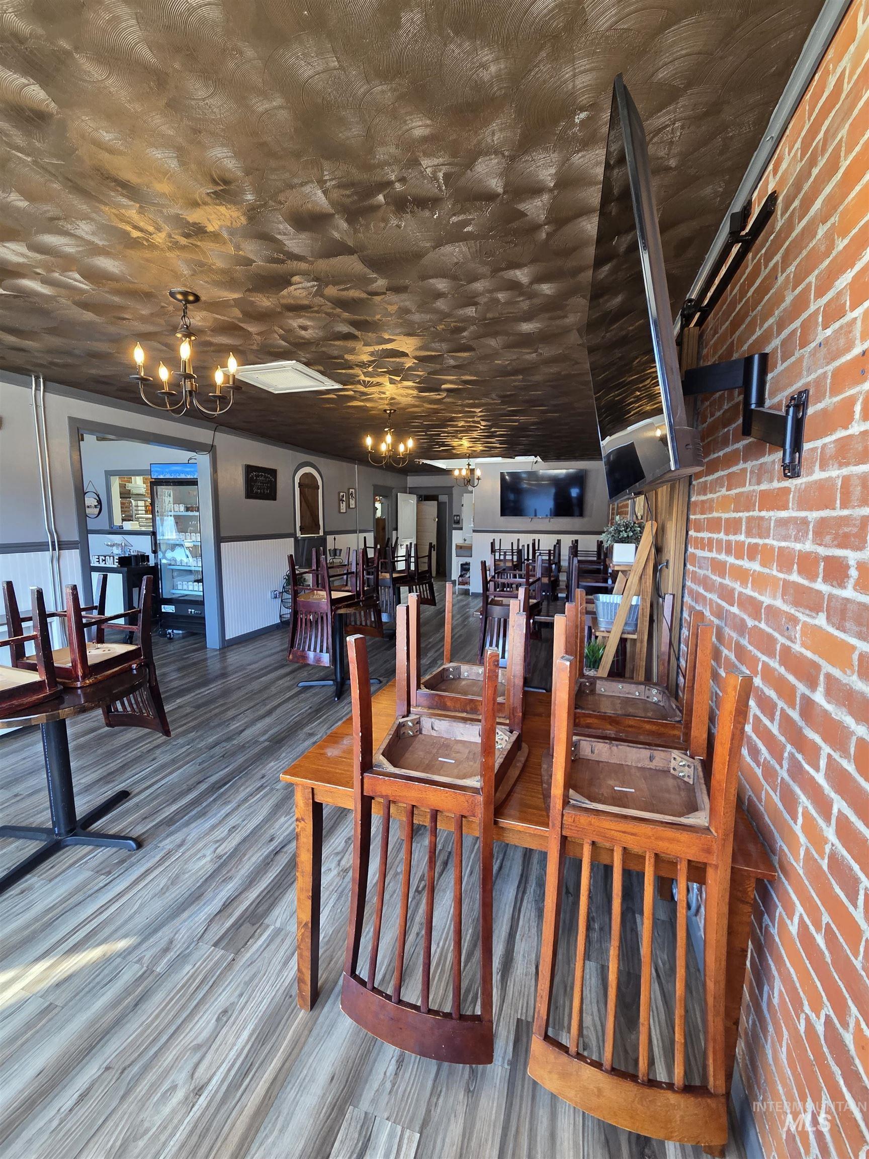 Commercial interior featuring wood-finish flooring, exposed brick wall, and a textured ceiling