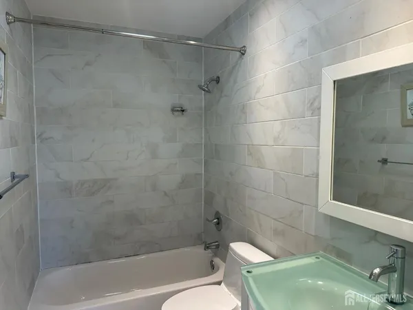 a bathroom with a granite countertop sink a mirror and shower