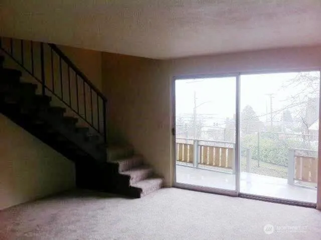 a view of an empty room with wooden floor and windows
