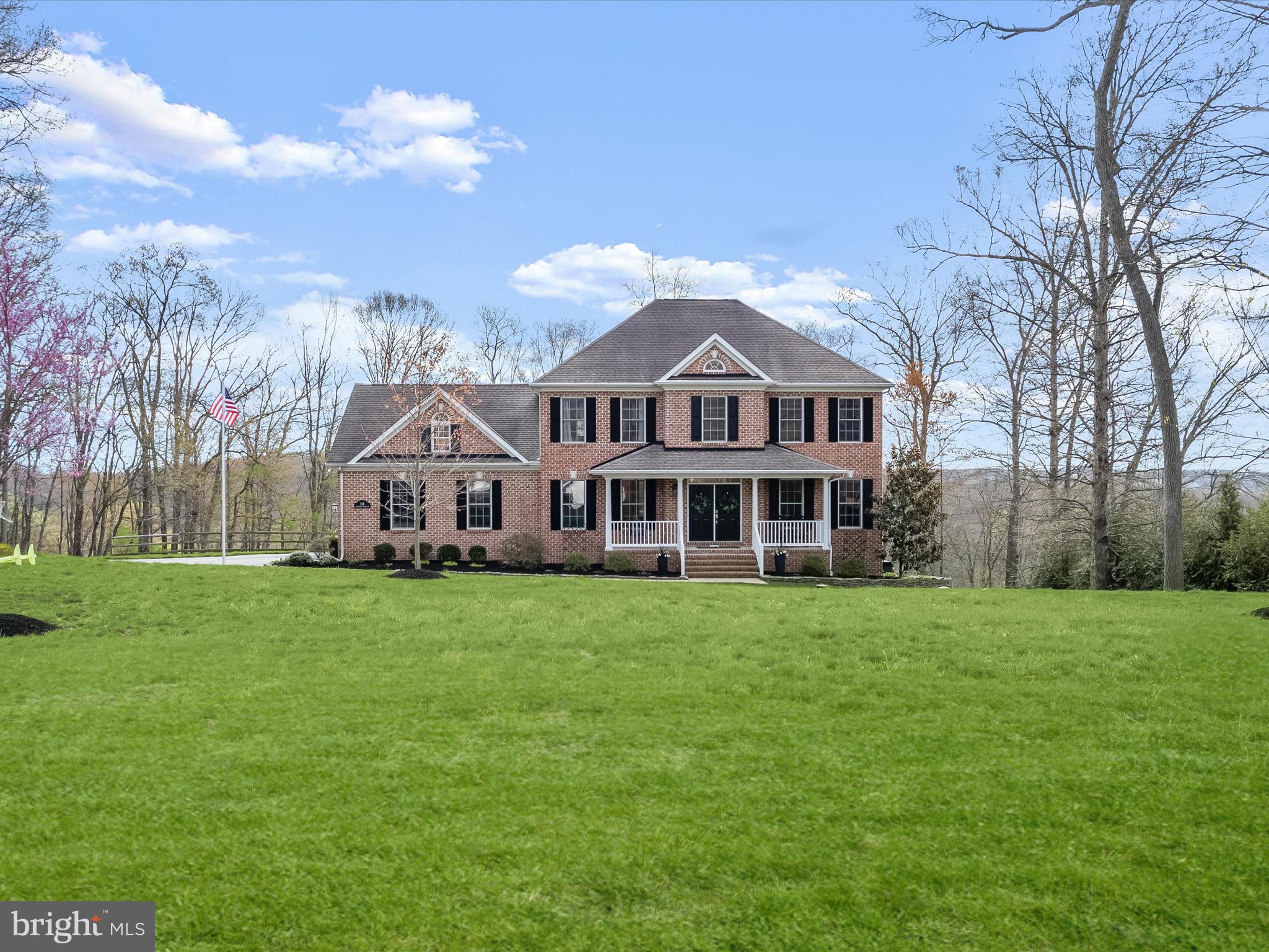 a view of a big house with a big yard and large trees