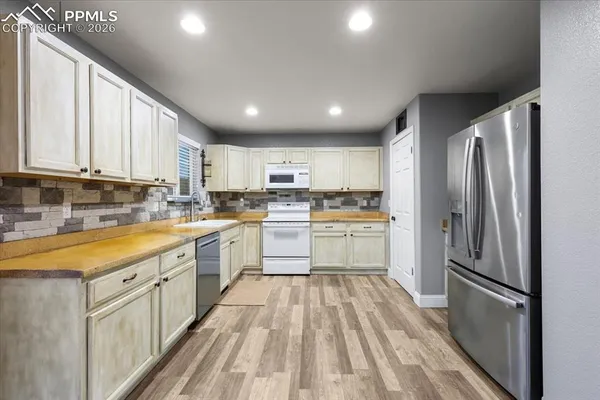 a kitchen with white cabinets stainless steel appliances and window