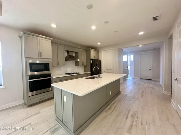 a large kitchen with stainless steel appliances a large counter top and a stove