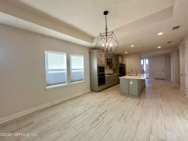 a view of a big room with wooden floor kitchen and windows