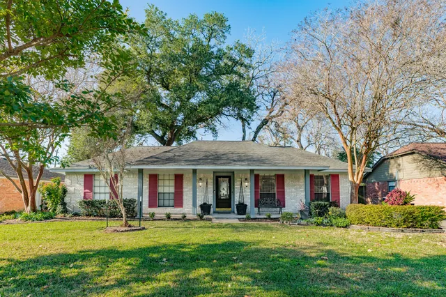 front view of a brick house with a big yard and large trees