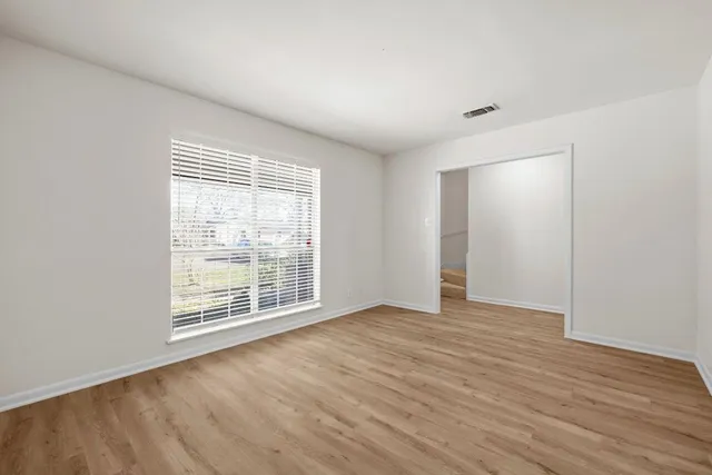 a view of an empty room with wooden floor and a window