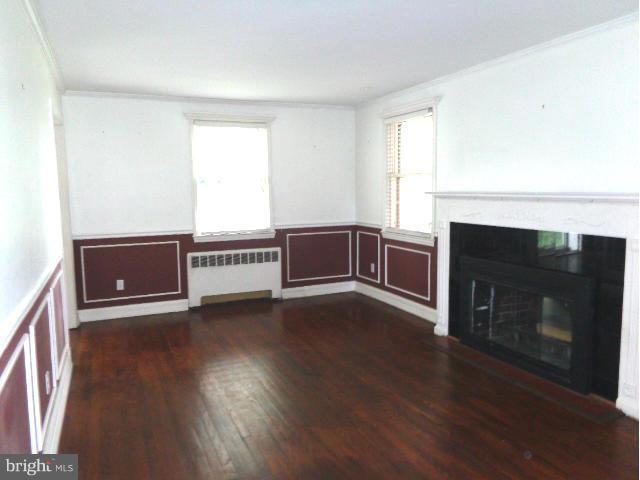 3002 Dunbrin Road Baltimore, MD 21222 - Photo 3 of 30 a view of an empty room with wooden floor fireplace and a window