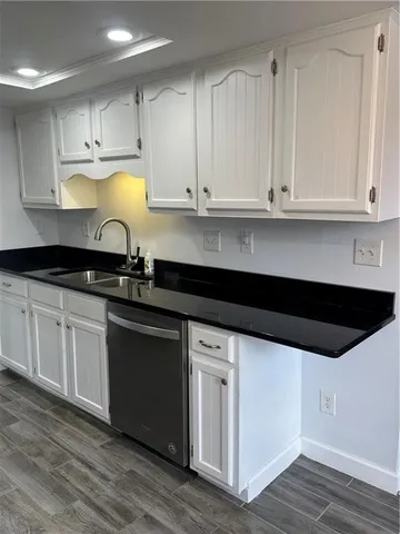 a kitchen with granite countertop white cabinets and a sink