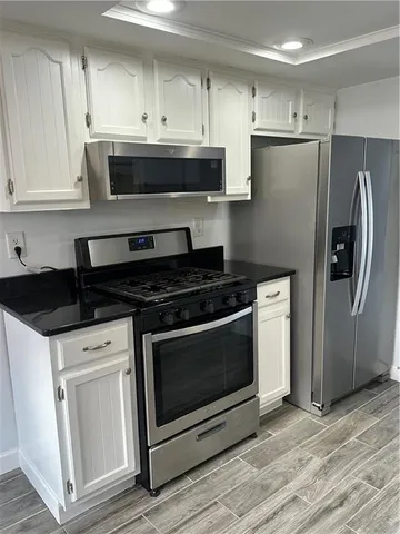 a kitchen with stainless steel appliances a stove a microwave and a hard wood floors