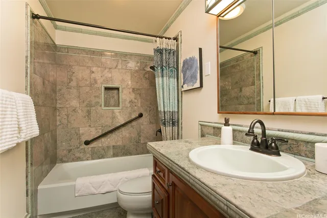 a bathroom with a granite countertop sink a toilet a mirror a bathtub and shower