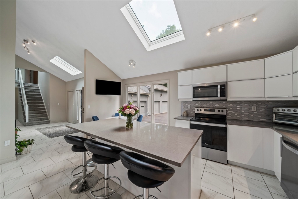 31 Dedham Street Sharon, MA 02067 - Photo 8 of 42 a kitchen with stainless steel appliances a stove a sink a microwave and chairs