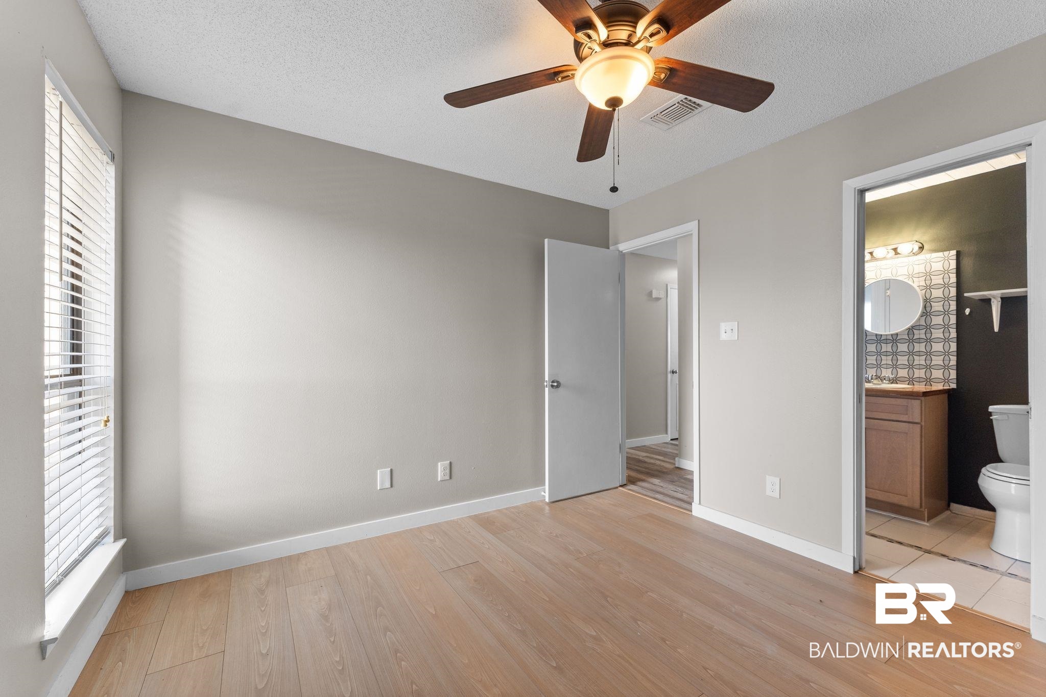 128 West Satsuma Avenue, Unit 128 Foley, AL 36535 - Photo 15 of 41 Unfurnished bedroom featuring light wood-style floors, ceiling fan, a textured ceiling, and ensuite bath