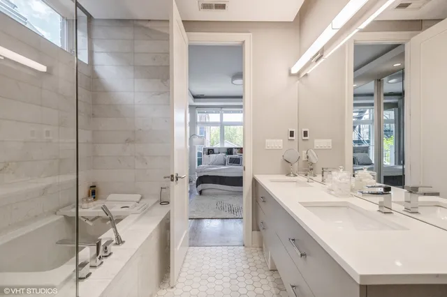 a bathroom with a double vanity sink a mirror and a bathtub