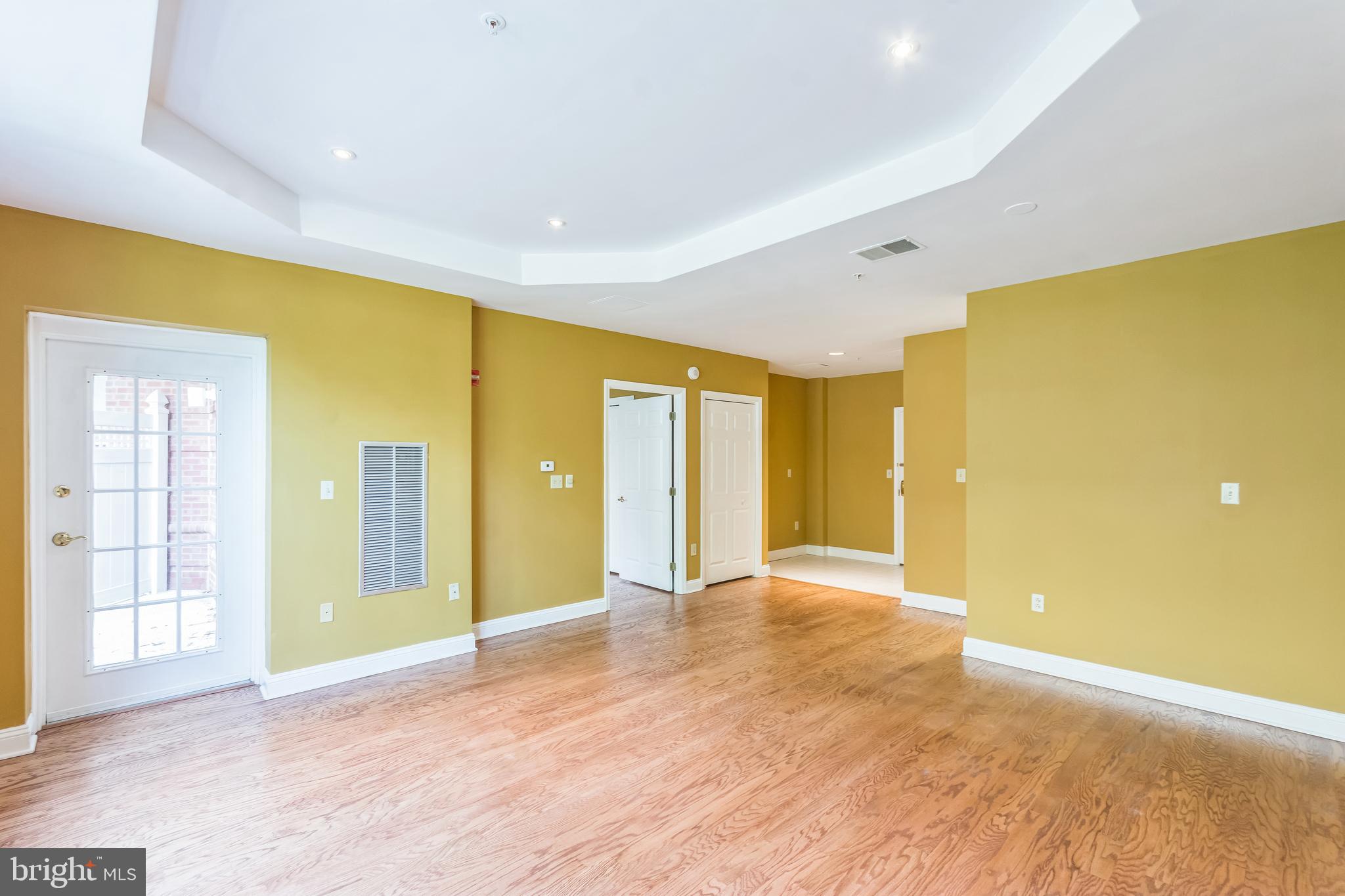 a view of an empty room with wooden floor and windows