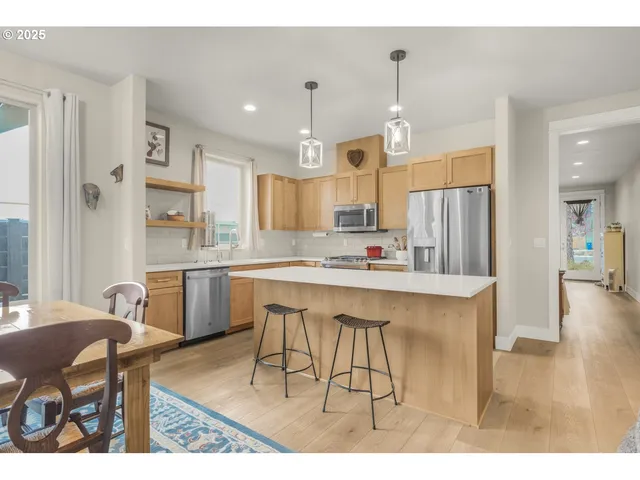 a kitchen with stainless steel appliances kitchen island granite countertop a dining table chairs sink and cabinets