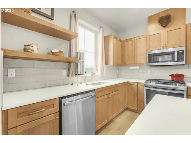 a kitchen with kitchen island granite countertop a sink cabinets and stainless steel appliances