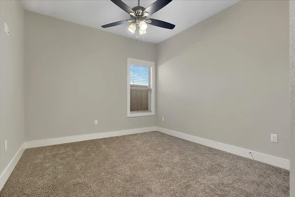 an empty room with a window and a fan