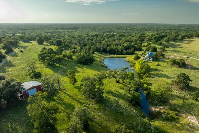 an aerial view of residential houses with outdoor space and trees