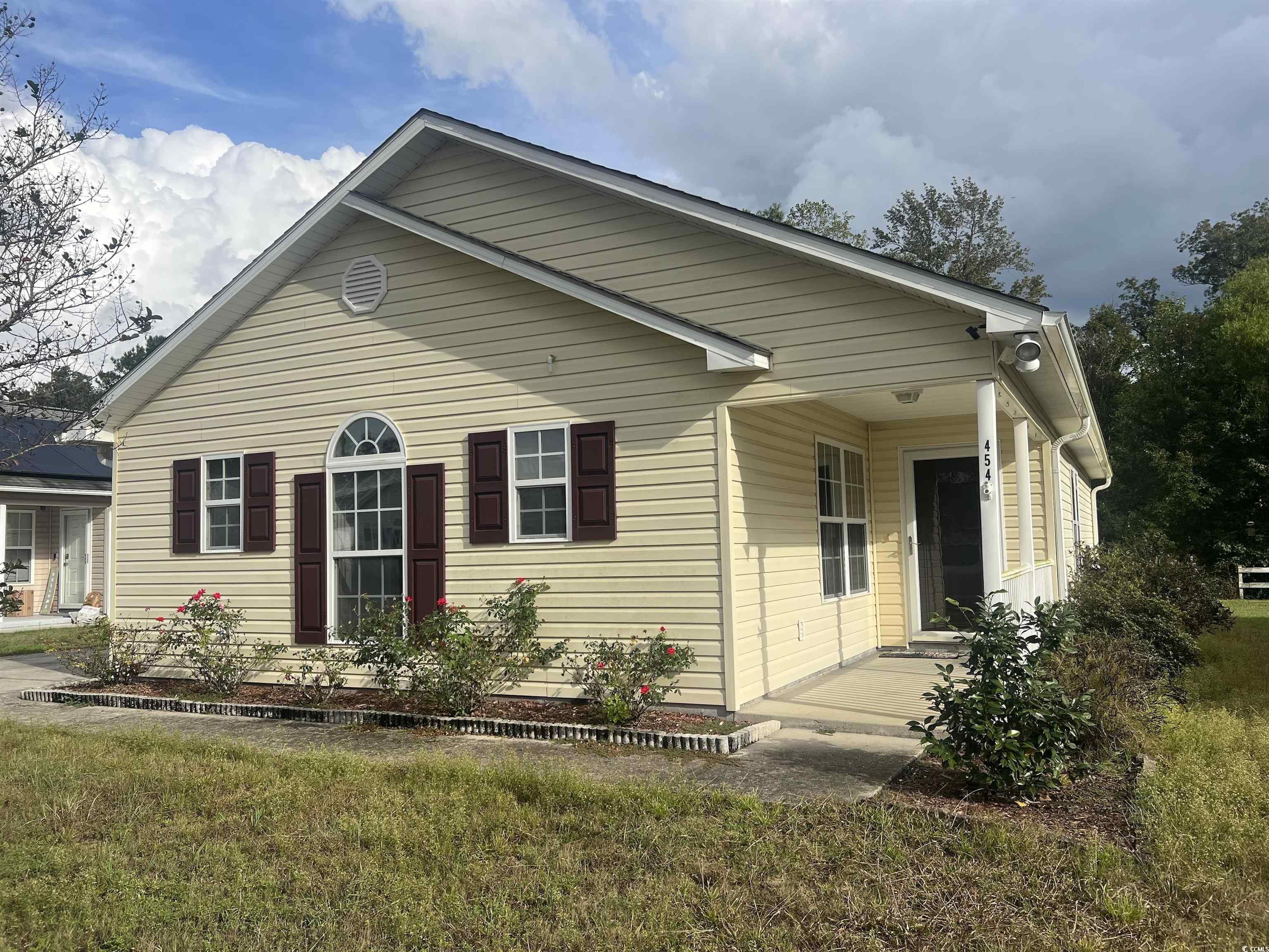 View of property exterior featuring a yard and covered porch